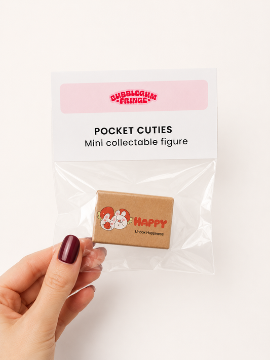 A hand with dark burgundy nail polish holds a clear plastic bag containing a small collectible figure. The packaging card reads 'BUBBLEGUM FRINGE' and 'POCKET CUTIES Mini collectable figure'.