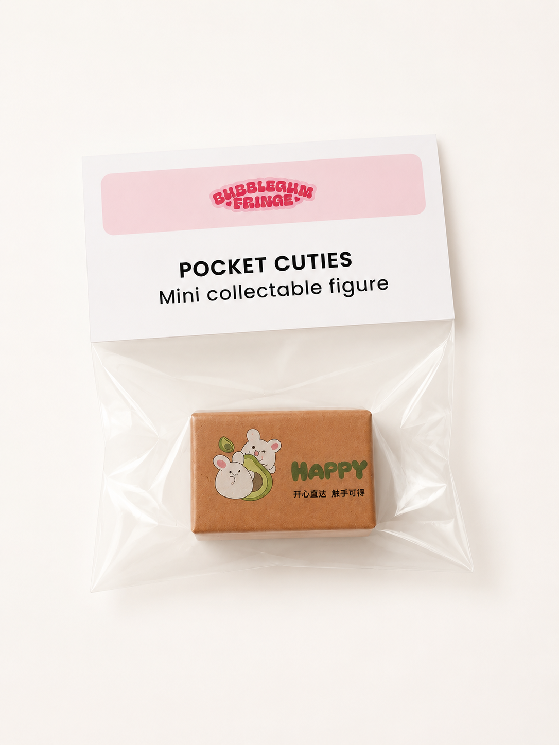 A packaged mini collectable figure from Bubblegum Fridge, labeled 'POCKET CUTIES'. The figure is a small brown cardboard box with a cute cartoon rabbit illustration and the word 'HAPPY' on the front, sealed inside a clear plastic bag with a white paper header card.