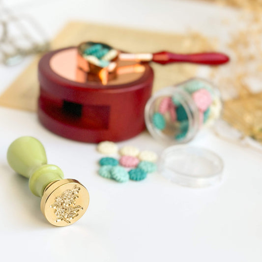 25mm Brass wax seal flower stamp with green, wooden handle. Next to wooden wax furnace.